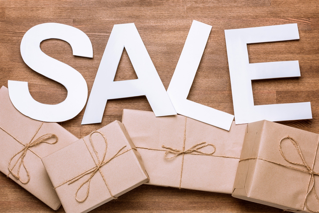 Sale sign with gift boxes on wooden surface